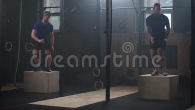 适合运动的两个人在废弃的工厂健身房做盒子跳跃。 剧烈运动是他每天交叉健身的一部分